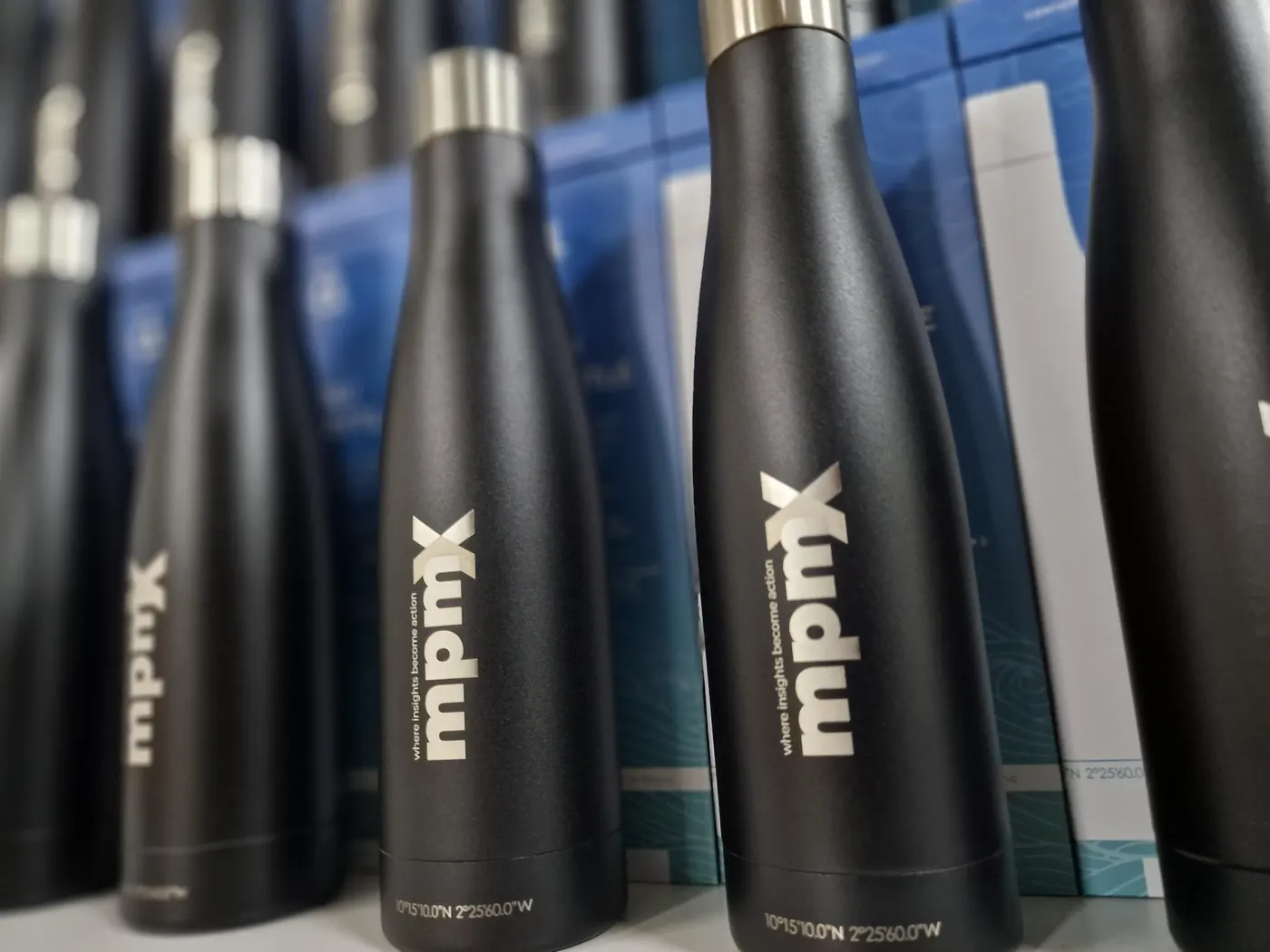Schwarze Edelstahlflaschen mit graviertem mpmX-Logo im Regal
